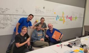 A bored woman wearing a business suit is playing with Post-it Notes in her office instead of working.