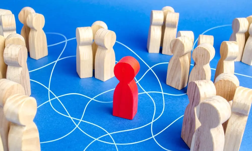 A business leader stands in the center of groups of employees, illustrated with wooded peg figures.