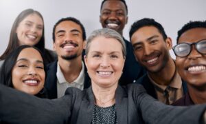A smiling female executive stands with her smiling, diverse team behind her.