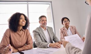A three—person panel conducts a job interview.