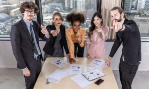 A team of business people goes over results, pointing fingers at someone out of frame.