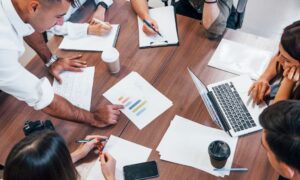 Four business people meeting. On the table is a bar chart indicating company growth.