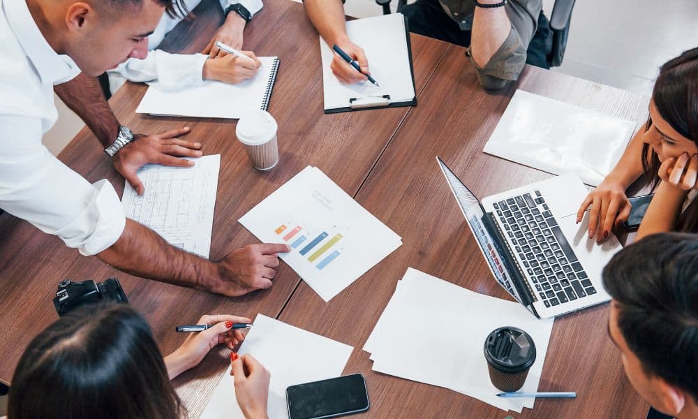 Four business people meeting. On the table is a bar chart indicating company growth.