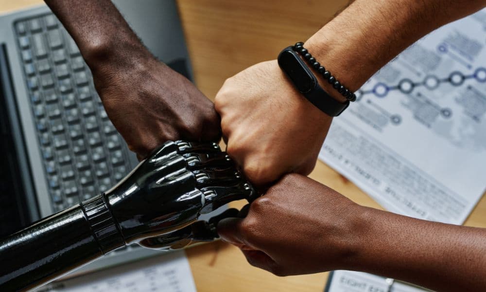 Human hands coming together in a gesture of unity beside a robotic arm.