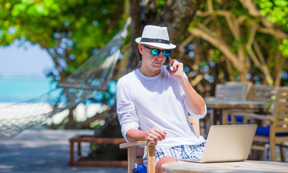 Business owner calling the office by cell phone on a white beach