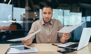 Frustrated leader reviews documents in office.
